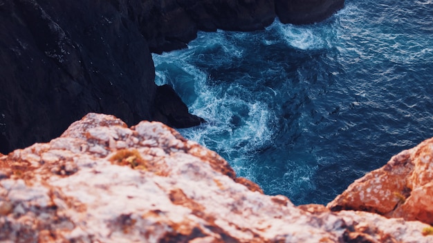 Hermosa foto aérea del cuerpo de agua con texturas sorprendentes golpeando los acantilados en el mar