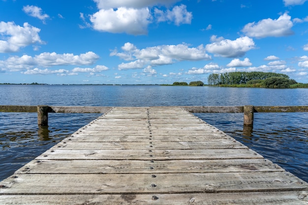 Hermosa foto de un antiguo embarcadero de madera de tablones bajo un cielo nublado azul