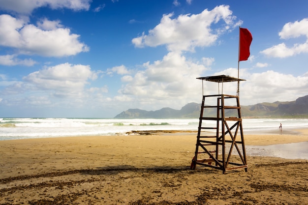 Hermosa foto de un asiento de salvavidas de playa con una bandera roja en Mallorca