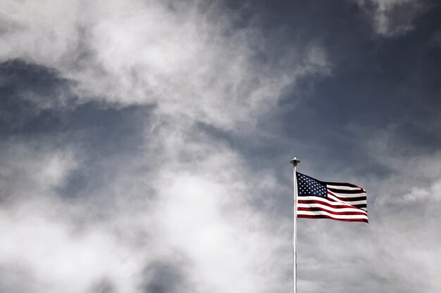 Hermosa foto de la bandera estadounidense ondeando en un poste blanco con increíble cielo nublado