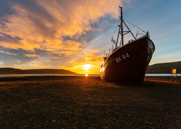 Una hermosa foto de un barco de pesca acercándose a la playa al amanecer.