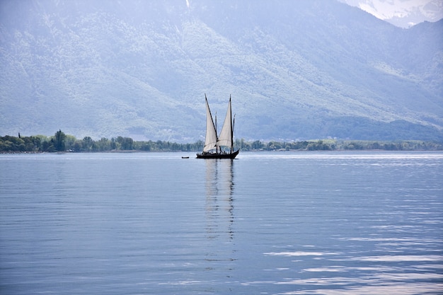 Foto gratuita hermosa foto de un barco que navega en el agua con montañas boscosas