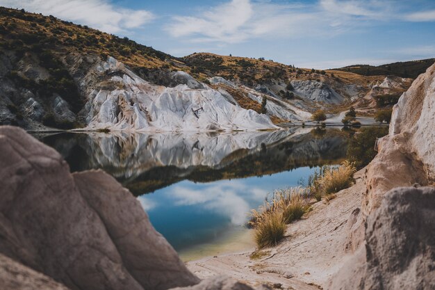 Hermosa foto de Blue Lake rodeado de colinas bajo un cielo azul en Nueva Zelanda