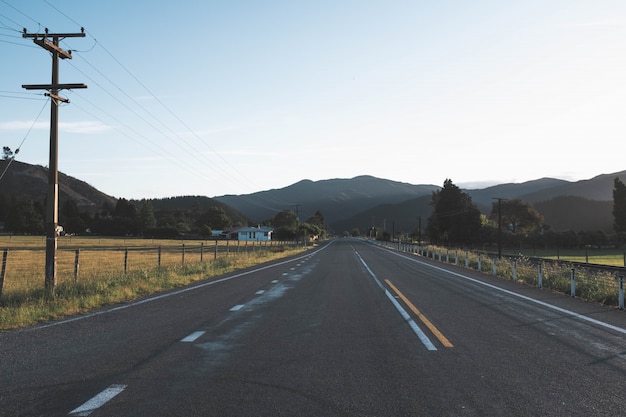 Hermosa foto de un camino solitario vacío gris en el campo con montañas