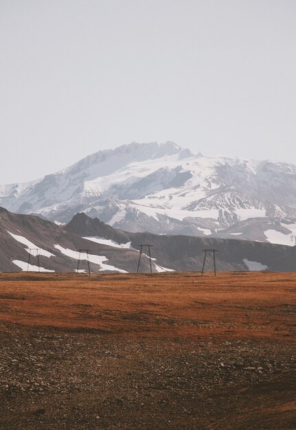 Hermosa foto de un campo fangoso con increíbles montañas nevadas