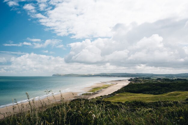 Hermosa foto de un campo de hierba cerca de la orilla de la playa bajo un cielo nublado en Francia