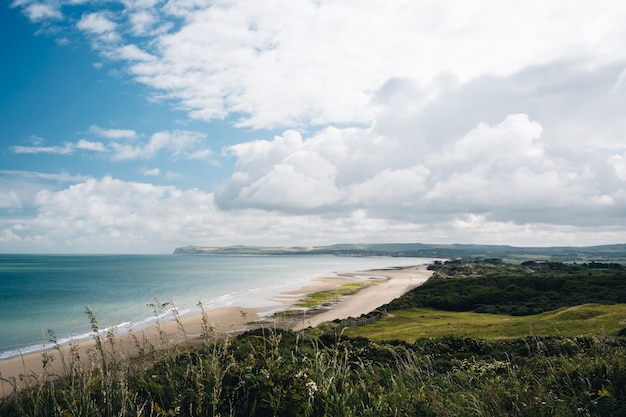 Hermosa foto de un campo de hierba cerca de la orilla de la playa bajo un cielo nublado en Francia