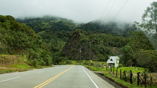 Hermosa foto de una carretera curva vacía en el campo con nubes increíbles durante un día brumoso