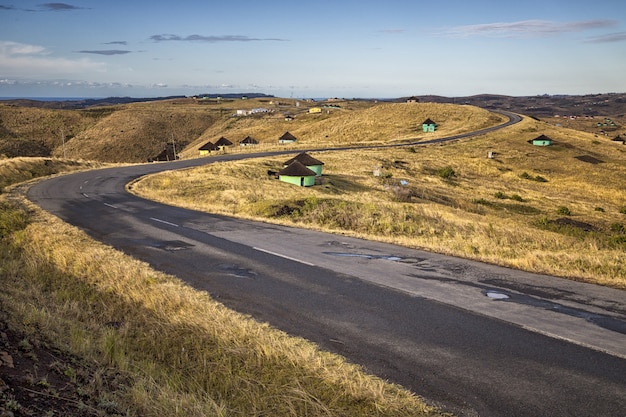 Hermosa foto de una carretera con curvas con pequeñas casas a los lados y un cielo azul