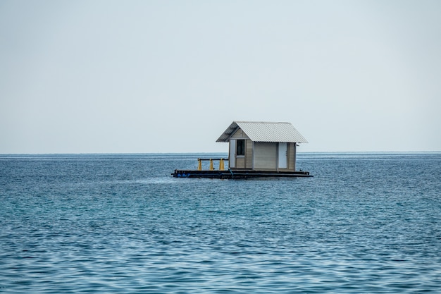 Hermosa foto de una casa flotante en un océano azul con un cielo blanco claro en el