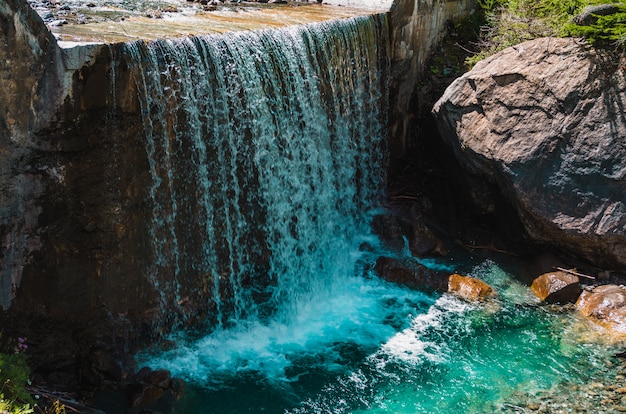 Hermosa foto de una cascada cerca de enormes formaciones rocosas en Pragelato, Italia