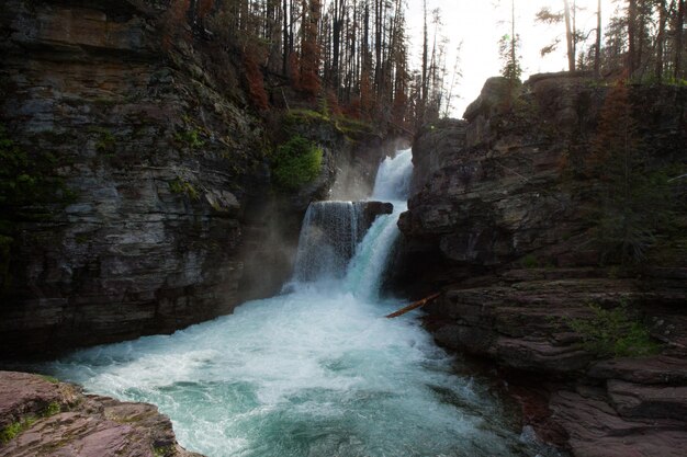 Hermosa foto de una cascada en medio de un acantilado rodeado de árboles