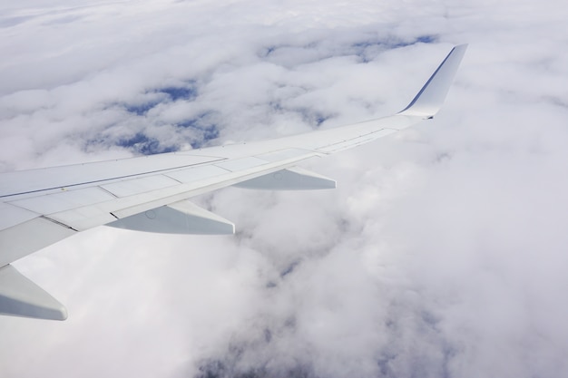 Hermosa foto del cielo lleno de nubes y un ala de avión desde la ventana del avión