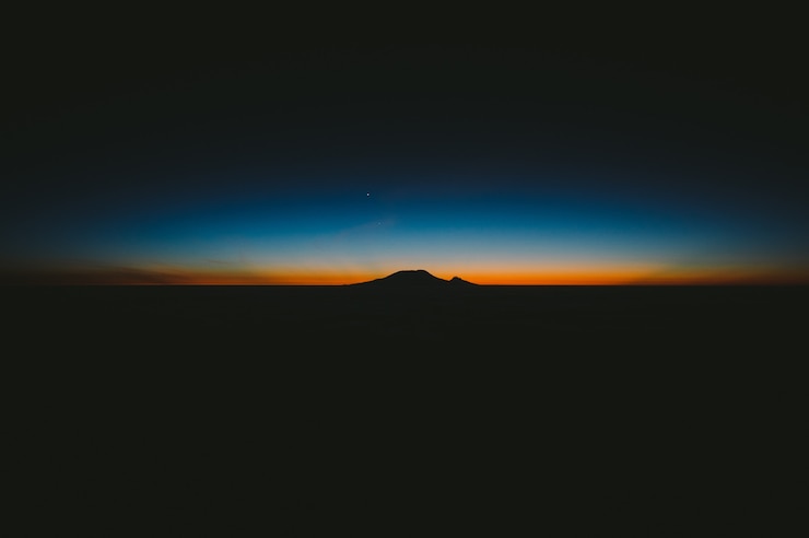 Foto gratuito hermosa foto de colinas oscuras con la increíble puesta de sol naranja y azul en el horizonte
