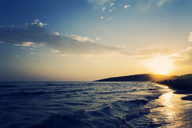 Hermosa foto de la costa arenosa del mar con una increíble puesta de sol