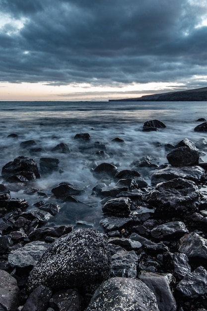 Hermosa foto de la costa rocosa del mar con una increíble textura de agua y un impresionante cielo gris nublado