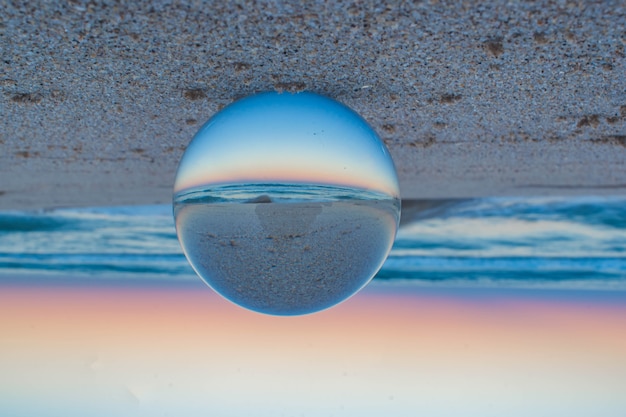 Hermosa foto creativa de una playa con una bola de lente de cristal