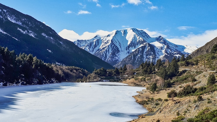 Foto gratuito hermosa foto de una cumbre con un lago congelado y un terreno con árboles y arbustos