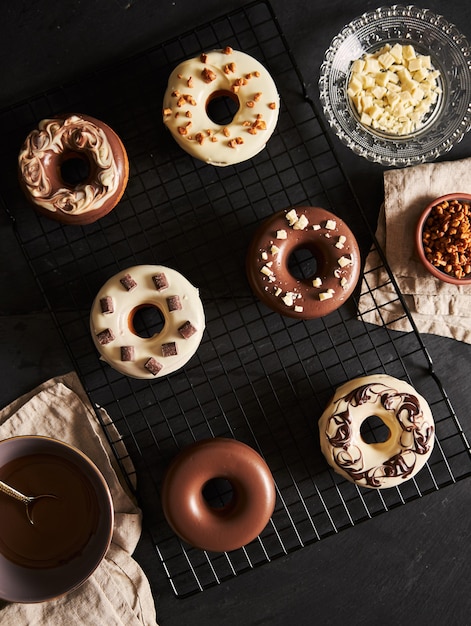 Hermosa foto de deliciosas donas cubiertas con el glaseado de chocolate con los ingredientes sobre una mesa