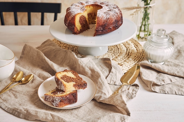 Hermosa foto de un delicioso pastel de anillo puesto en un plato blanco y una flor blanca cerca de él