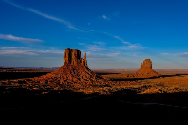 Hermosa foto del desierto con arbustos secos y grandes acantilados en la distancia bajo un cielo azul