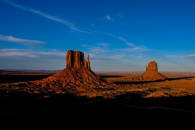 Hermosa foto del desierto con arbustos secos y grandes acantilados en la distancia bajo un cielo azul