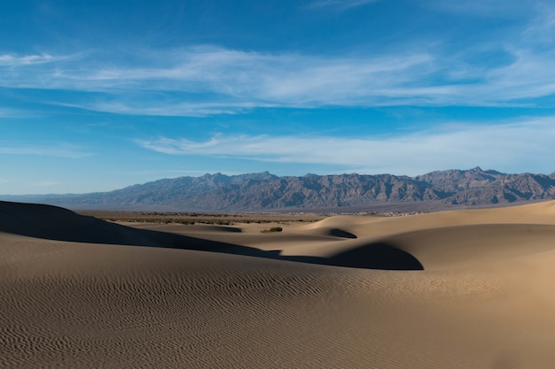 Foto gratuita hermosa foto de un desierto con senderos en la arena y colinas rocosas bajo el cielo tranquilo