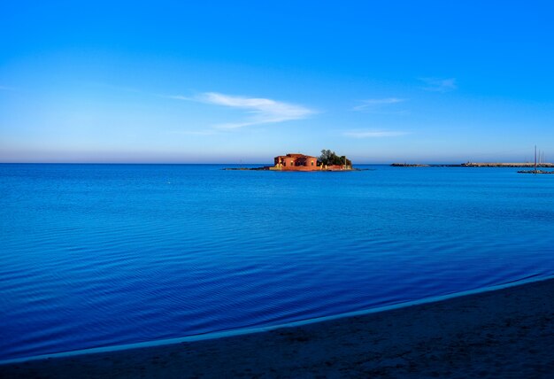 Hermosa foto de una gran casa en medio del mar bajo un cielo azul