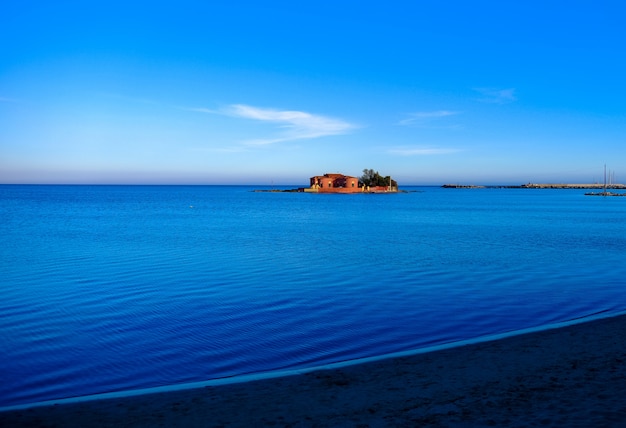 Hermosa foto de una gran casa en medio del mar bajo un cielo azul