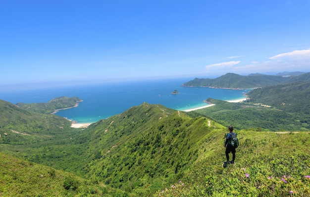 Foto gratuita hermosa foto de un hombre de pie sobre un paisaje de colinas boscosas y un océano azul