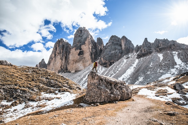 Hermosa foto de un hombre de pie sobre una roca con colinas
