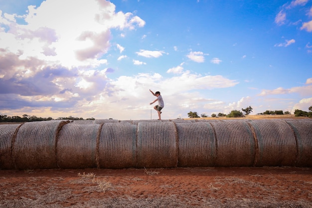 Hermosa foto de un joven equilibrio sobre pilas de heno