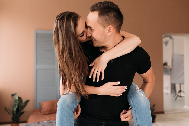 Hermosa foto de un joven sosteniendo a su novia en la espalda