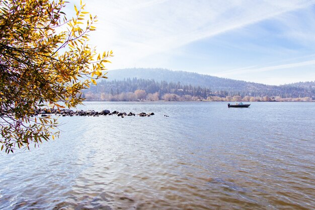 Hermosa foto de un lago con un barco navegando en él con un cielo soleado