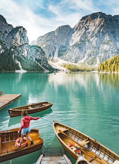 Una hermosa foto de un lago con pocos barcos con una mujer parada en uno de ellos.