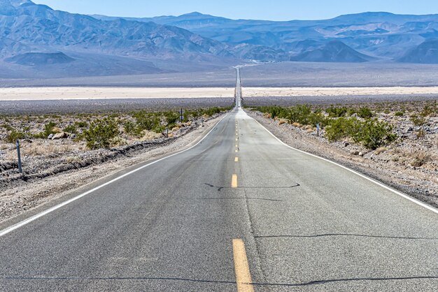 Hermosa foto de un largo camino de hormigón recto entre el campo del desierto