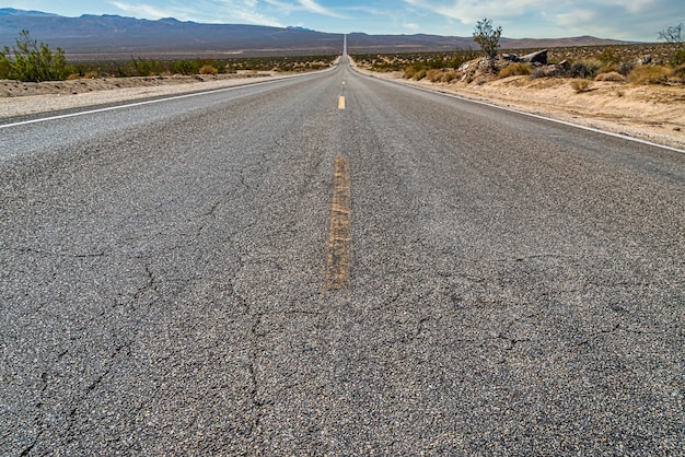 Hermosa foto de un largo camino de hormigón recto entre el campo del desierto