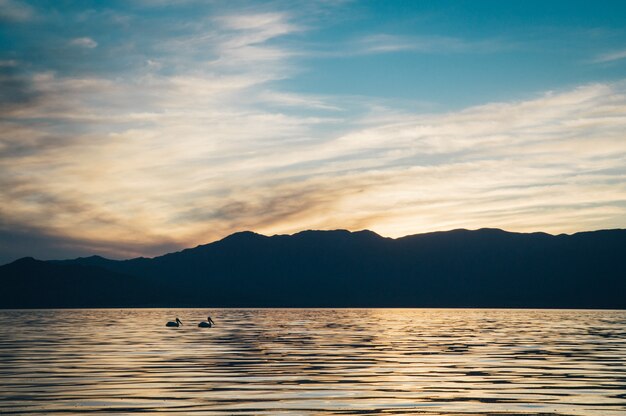 Hermosa foto del mar con colinas oscuras y un cielo increíble al atardecer