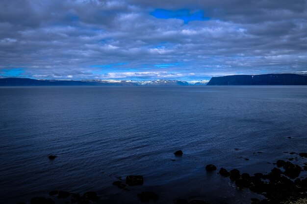 Hermosa foto de un mar y montañas en la distancia bajo un cielo nublado