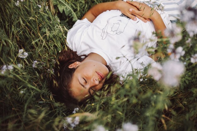 Hermosa foto de una modelo que se establecen en un campo de margaritas con los ojos cerrados