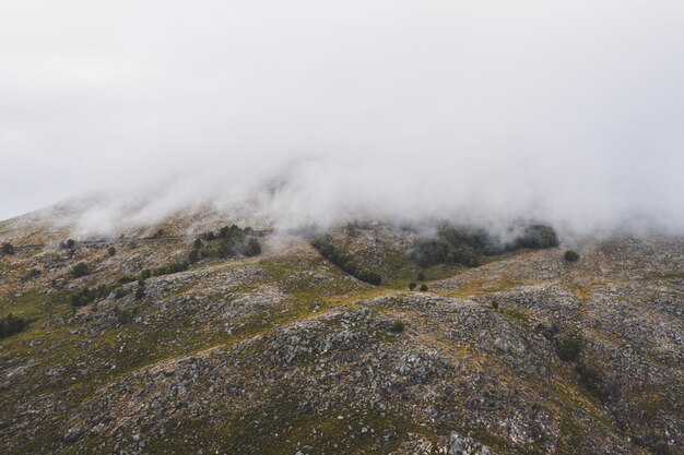 Hermosa foto de una montaña cubierta de espesas nubes blancas