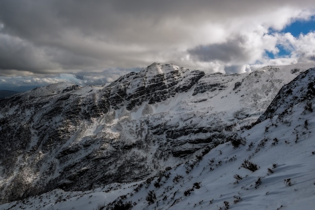 Hermosa foto de una montaña cubierta de nieve y nubes espesas que cubren el cielo azul