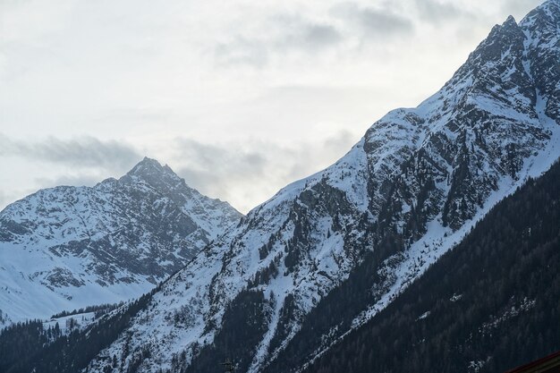 Hermosa foto de una montaña escarpada cubierta de nieve blanca con un cielo nublado