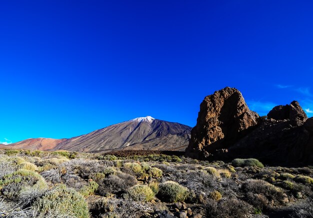 Hermosa foto de una montaña, grandes rocas y plantas verdes en un cielo azul claro