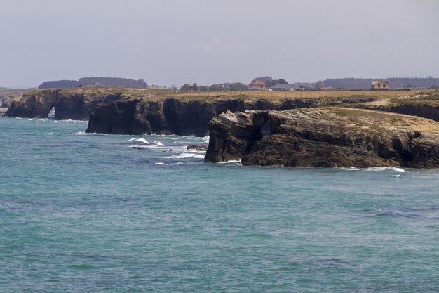 Hermosa foto de montañas rocosas bañadas por las olas del océano azul