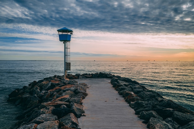 Hermosa foto de un muelle rodeado de piedras que conducen al mar al atardecer