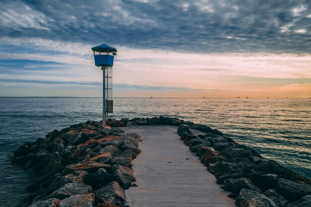 Hermosa foto de un muelle rodeado de piedras que conducen al mar al atardecer