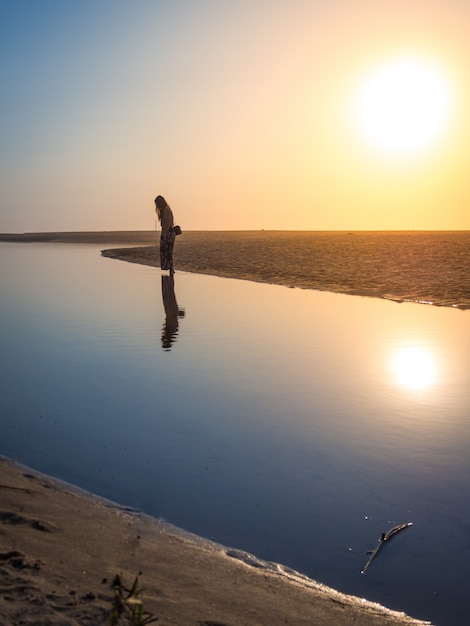 Hermosa foto de una mujer caminando por la playa bajo la luz del sol