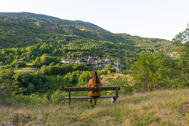 Hermosa foto de una mujer sentada en el banco frente a un paisaje de montaña