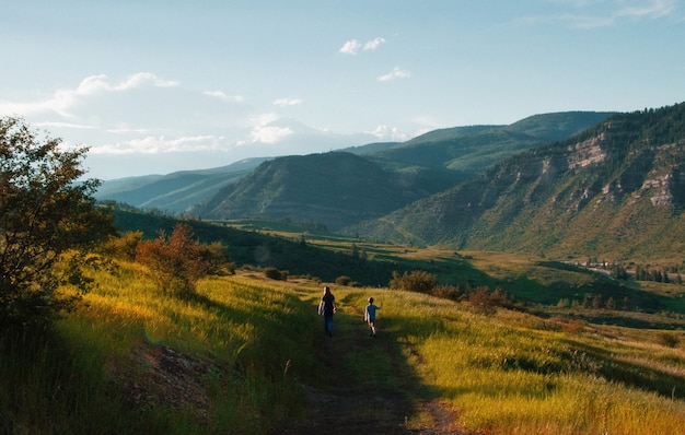 Hermosa foto de un niño y un hombre caminando por un sendero en medio de campos de hierba